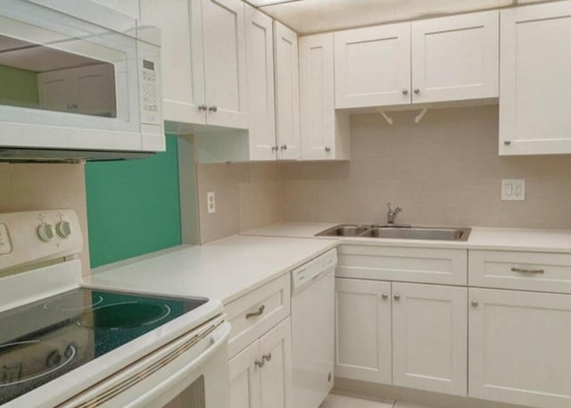 kitchen with white cabinetry, white appliances, and sink