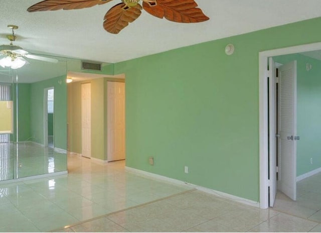 empty room with ceiling fan, a textured ceiling, and light tile patterned floors