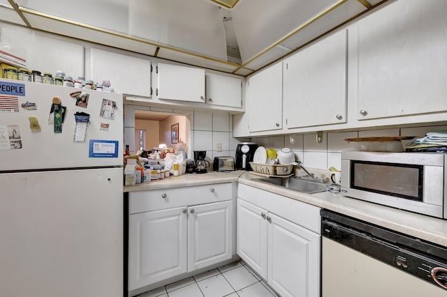 kitchen with a sink, white appliances, white cabinets, light countertops, and light tile patterned floors