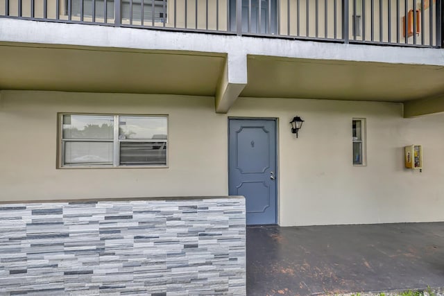 doorway to property with stucco siding, stone siding, and board and batten siding