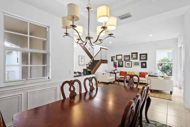 tiled dining area featuring a chandelier and a raised ceiling