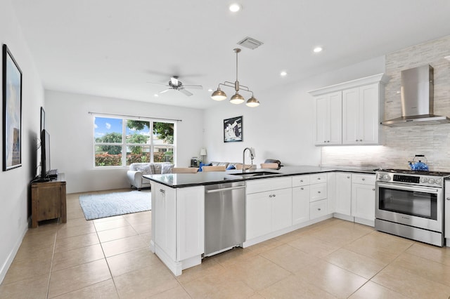 kitchen featuring wall chimney range hood, sink, light tile flooring, and appliances with stainless steel finishes