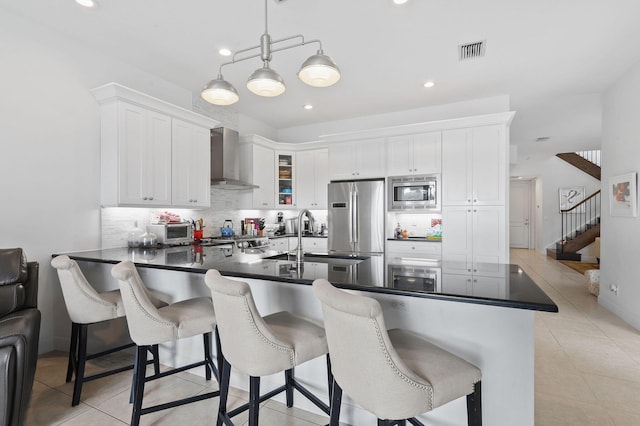 143 Isle Verde Way, Palm Beach Gardens, FL 33418 - kitchen featuring appliances with stainless steel finishes, wall chimney range hood, a sink, dark countertops, and a peninsula