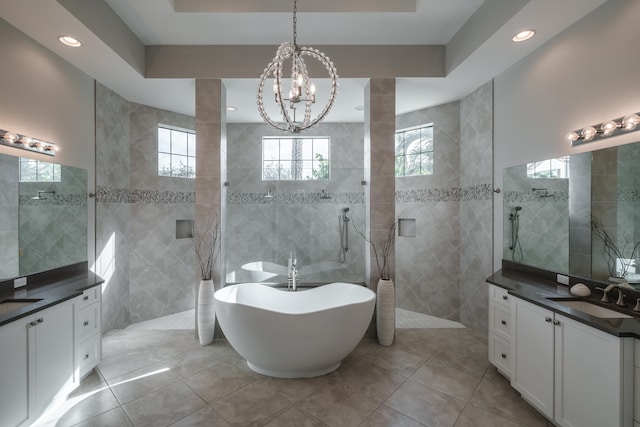 bathroom featuring a raised ceiling, tile patterned flooring, tile walls, dual bowl vanity, and a notable chandelier