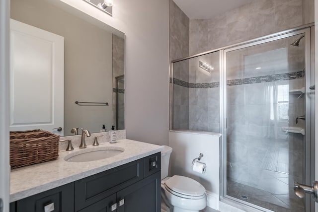 bathroom featuring a shower with door, toilet, and vanity