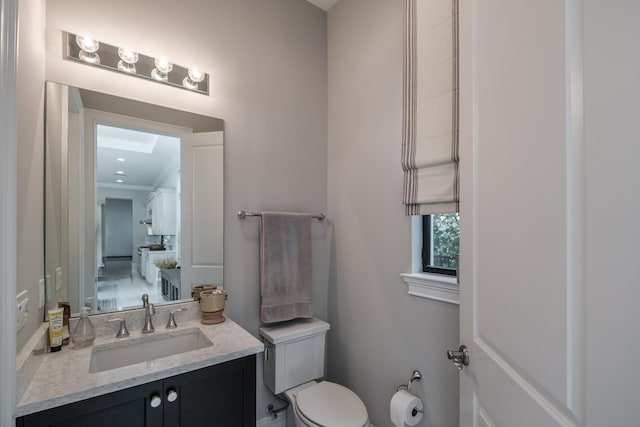 bathroom with toilet, ornamental molding, and vanity