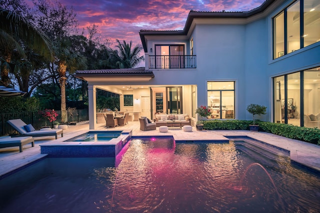 pool at dusk with an outdoor living space, an in ground hot tub, and a patio area