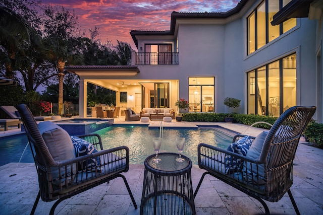 pool at dusk featuring a patio area, an outdoor living space, and pool water feature