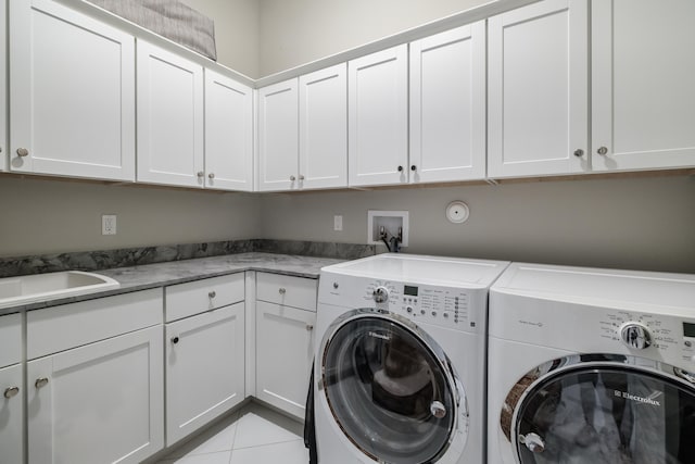 laundry room featuring sink, washer and clothes dryer, light tile patterned floors, and cabinets