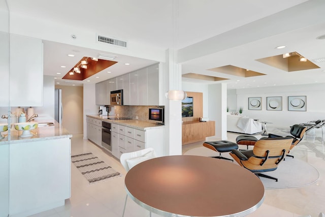 dining space with a raised ceiling, sink, and light tile patterned floors