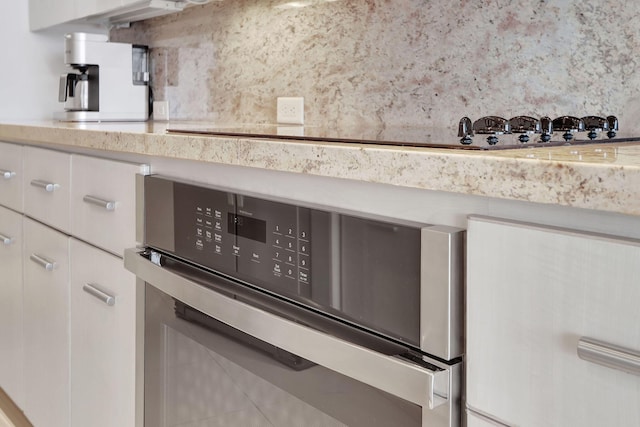 details featuring tasteful backsplash, white cabinets, oven, and a mail area