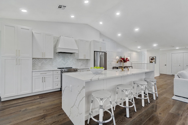 kitchen with stainless steel appliances, lofted ceiling, premium range hood, white cabinets, and dark wood-type flooring