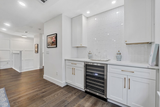 kitchen with wine cooler, dark hardwood / wood-style flooring, light stone counters, white cabinets, and decorative backsplash