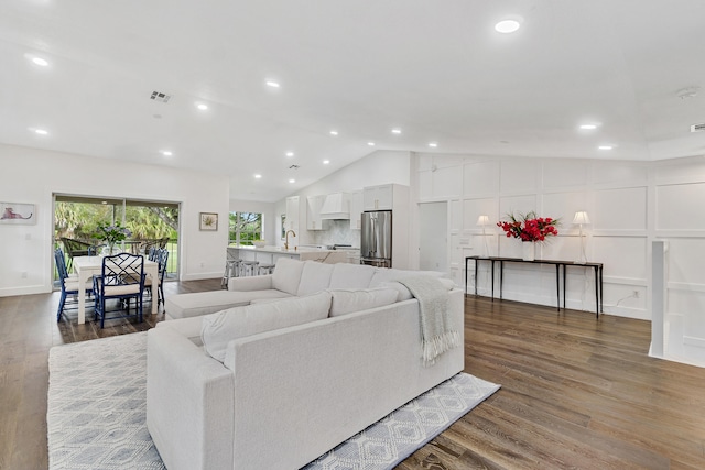 living room with wood-type flooring, vaulted ceiling, and sink