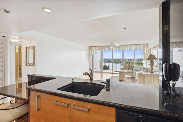 kitchen featuring dark stone counters, a textured ceiling, ceiling fan, sink, and dishwasher