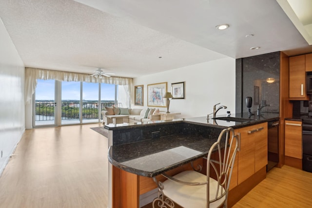 kitchen featuring a breakfast bar, kitchen peninsula, a wall of windows, and dark stone counters