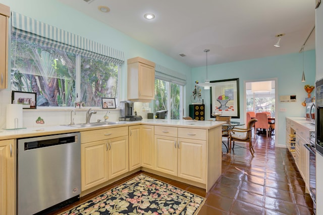 kitchen with sink, stainless steel dishwasher, dark tile patterned floors, and kitchen peninsula