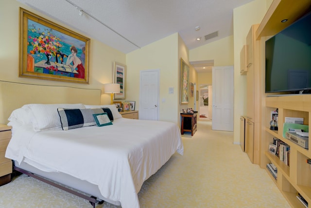 bedroom featuring track lighting, vaulted ceiling, light colored carpet, and a textured ceiling