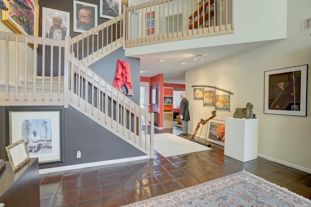 stairway featuring dark tile patterned floors and a towering ceiling