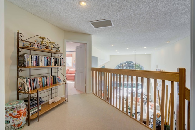 corridor featuring light carpet, a textured ceiling, and plenty of natural light