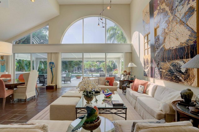 living room featuring dark tile patterned floors, a healthy amount of sunlight, and high vaulted ceiling