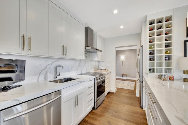 kitchen with sink, stainless steel appliances, white cabinets, and wall chimney exhaust hood