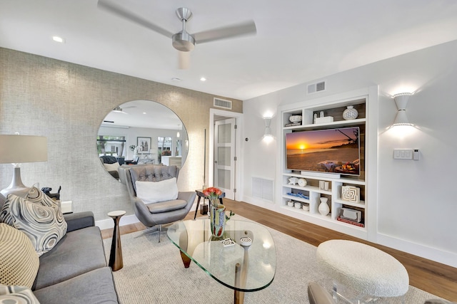 living room featuring hardwood / wood-style flooring, ceiling fan, and built in shelves