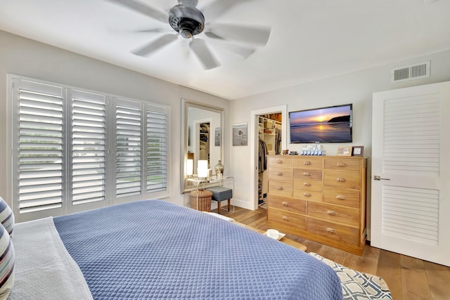 bedroom featuring wood-type flooring, a closet, ceiling fan, and a spacious closet