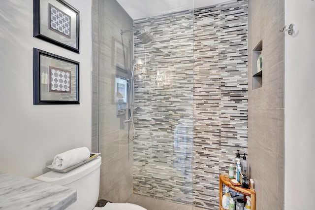 bathroom featuring a tile shower and toilet