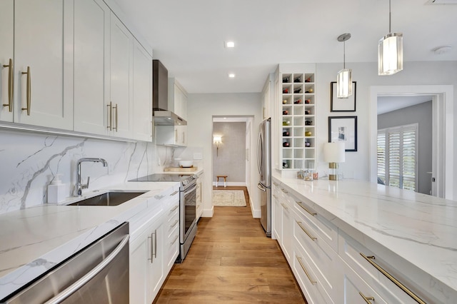 kitchen featuring stainless steel appliances, white cabinetry, sink, and wall chimney exhaust hood