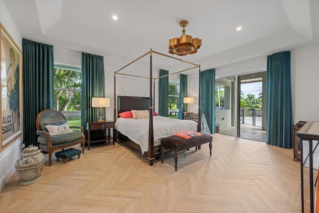 bedroom featuring multiple windows, light parquet flooring, and a tray ceiling