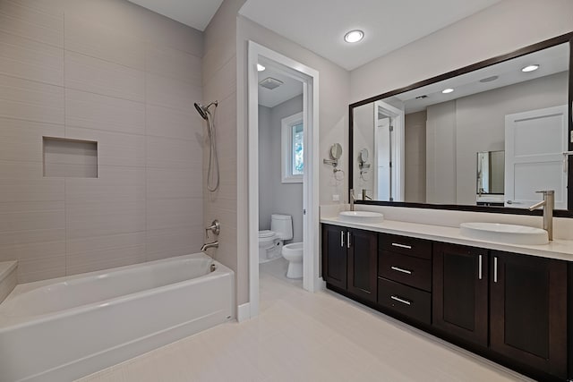 full bathroom with tiled shower / bath, toilet, a bidet, vanity, and tile patterned flooring