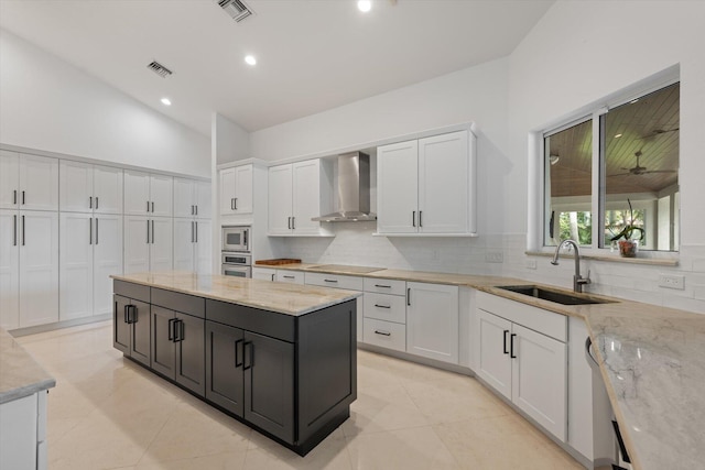 kitchen featuring white cabinetry, light stone counters, stainless steel appliances, and wall chimney range hood