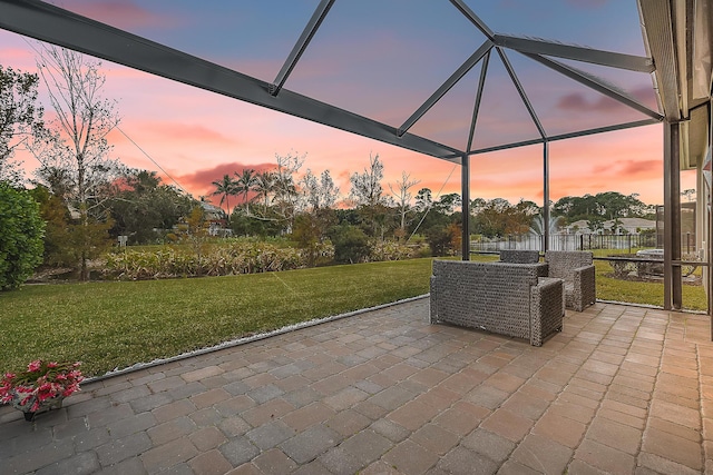 patio terrace at dusk featuring a lanai and a yard