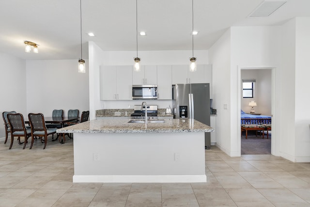 kitchen with light stone countertops, white cabinetry, decorative light fixtures, light tile flooring, and appliances with stainless steel finishes