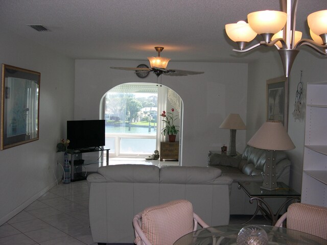 living room with a textured ceiling, light tile patterned floors, and ceiling fan