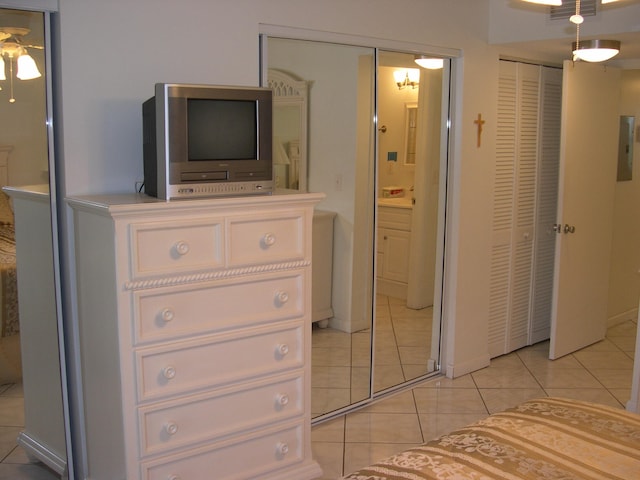 unfurnished bedroom with ceiling fan, light tile patterned floors, and two closets