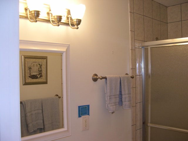 bathroom featuring a shower with door and an inviting chandelier