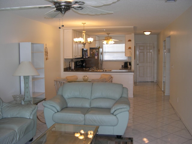 living room with ceiling fan with notable chandelier, light tile patterned floors, and a textured ceiling