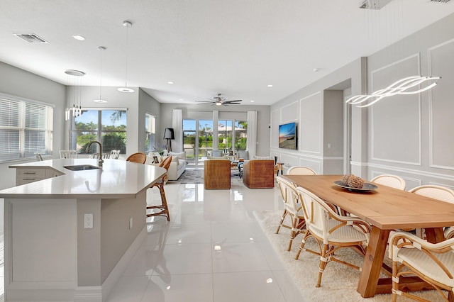 kitchen with sink, an island with sink, decorative light fixtures, light tile patterned flooring, and ceiling fan with notable chandelier