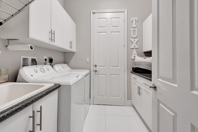 laundry room with washing machine and dryer, light tile patterned floors, and cabinets