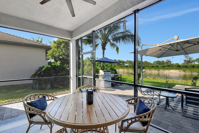 sunroom with a water view and ceiling fan