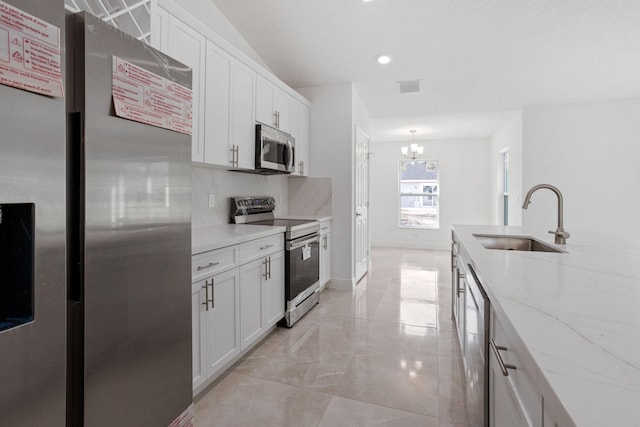 kitchen with backsplash, white cabinets, sink, a notable chandelier, and stainless steel appliances