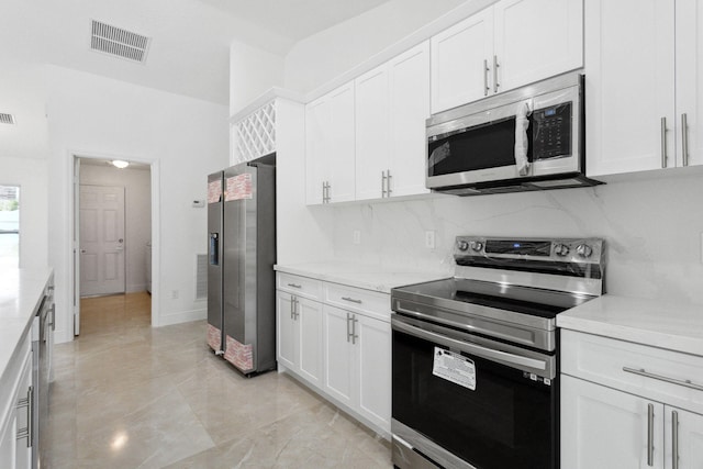 kitchen featuring light stone counters, white cabinetry, stainless steel appliances, and tasteful backsplash