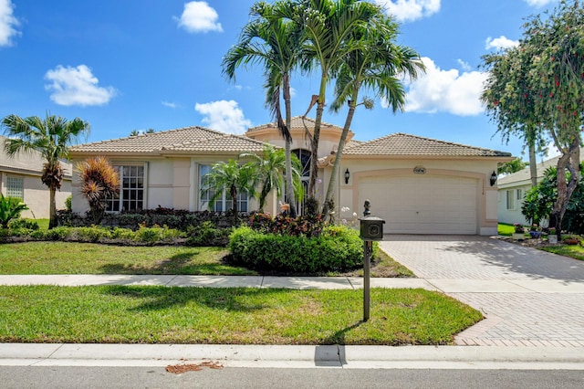 mediterranean / spanish-style house featuring a garage, a tiled roof, decorative driveway, and stucco siding