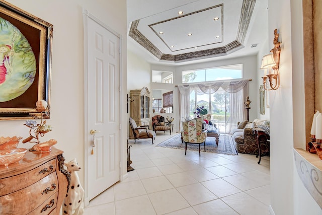 sitting room featuring ornamental molding, light tile patterned flooring, a raised ceiling, and a high ceiling