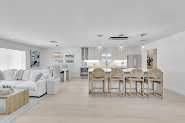 530 NW 14th St, Delray Beach, FL 33444 - kitchen featuring freestanding refrigerator, beverage cooler, white cabinetry, light countertops, and a breakfast bar area
