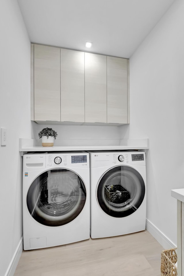 530 NW 14th St, Delray Beach, FL 33444 - clothes washing area featuring washer and clothes dryer, baseboards, cabinet space, and light wood-style flooring