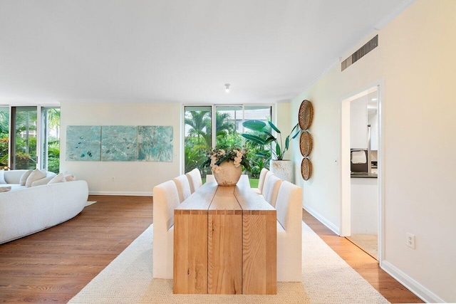 dining space featuring floor to ceiling windows, plenty of natural light, light hardwood / wood-style floors, and ornamental molding