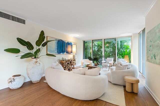 living room with crown molding, hardwood / wood-style floors, and a wall of windows